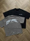 Black and gray t-shirts with 'END LABEL' branding on a wooden floor.